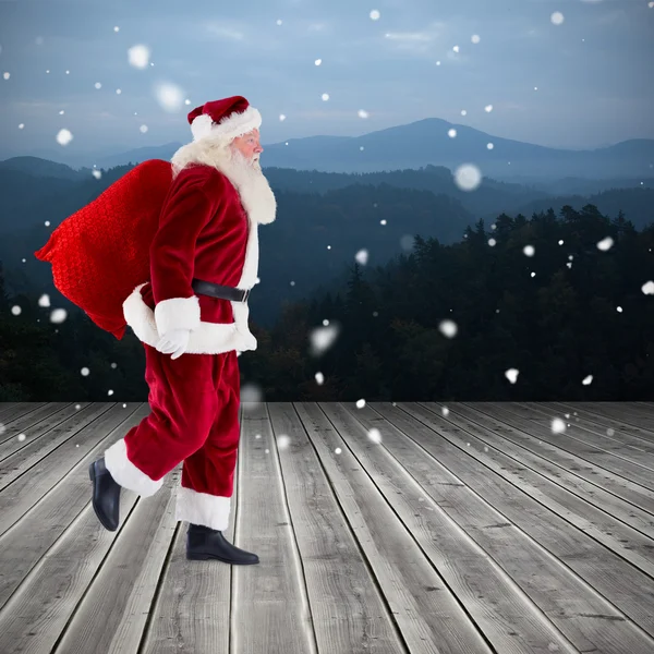 Santa carrying sack of gifts — Stock Photo, Image