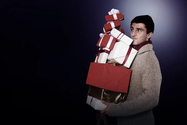 Молодой человек со многими рождественскими подарками — стоковое фото