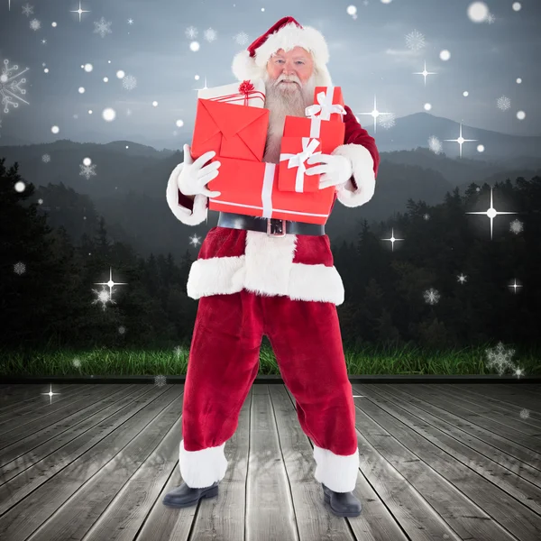 Composite image of santa carrying gifts — Stock Photo, Image