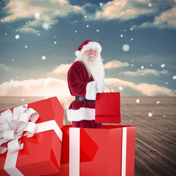 Composite image of santa standing in large gift — Stock Photo, Image