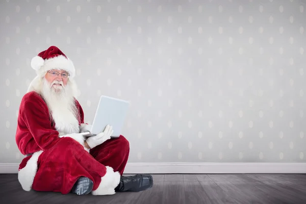 Santa sits and uses a laptop — Stock Photo, Image