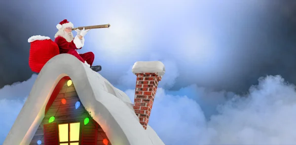 Santa sitting on roof of cottage — Stock Photo, Image