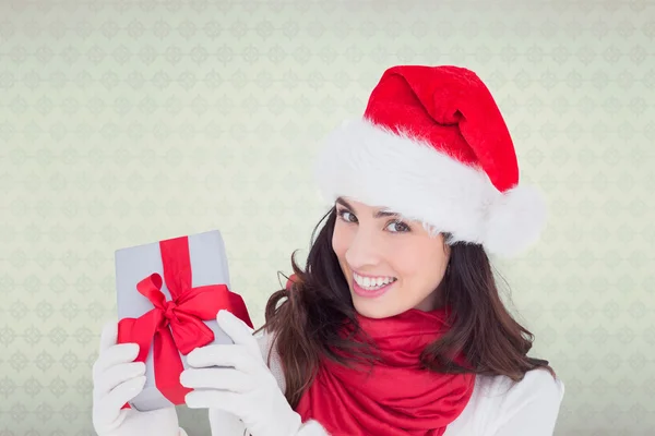 Excited brunette in santa hat showing gift — Stock Photo, Image