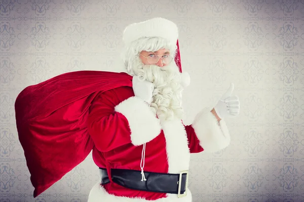 Papai Noel positivo com seu saco e polegares para cima — Fotografia de Stock