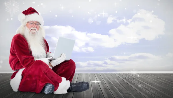 Santa sits and uses a laptop — Stock Photo, Image