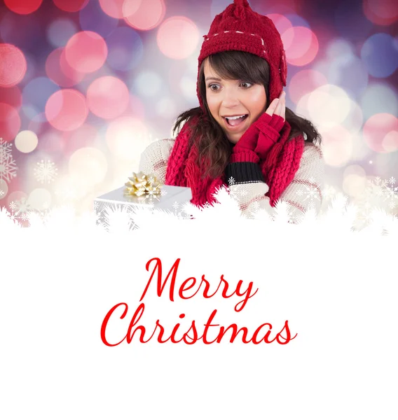 Surprised young woman holding a wrapped gift — Stock Photo, Image