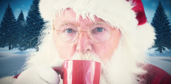 Santa bebiendo de una taza roja —  Fotos de Stock