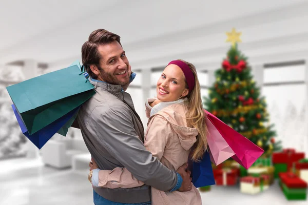 Lächelndes Paar mit Einkaufstüten, die sich umarmen — Stockfoto