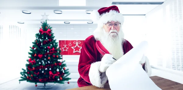 Zusammengesetzte Bild des Weihnachtsmannes schreibt etwas mit einer Feder — Stockfoto