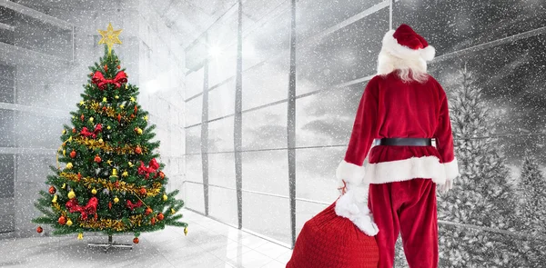 Zusammengesetztes Bild des Weihnachtsmannes, der einen Sack voller Geschenke trägt — Stockfoto