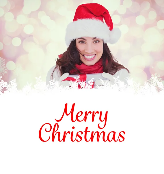 Festive brunette in santa hat holding gift — Stock Photo, Image