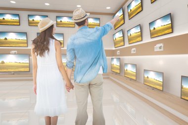 couple looking against televisions for sale clipart