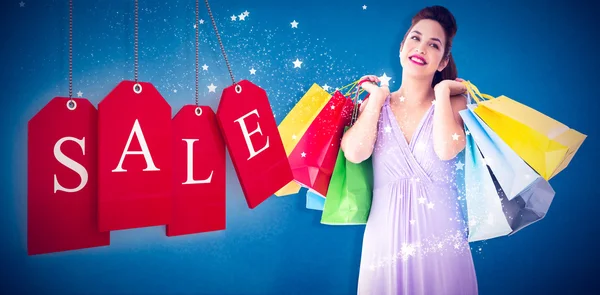 Thoughtful brunette holding shopping bags — Stock Photo, Image