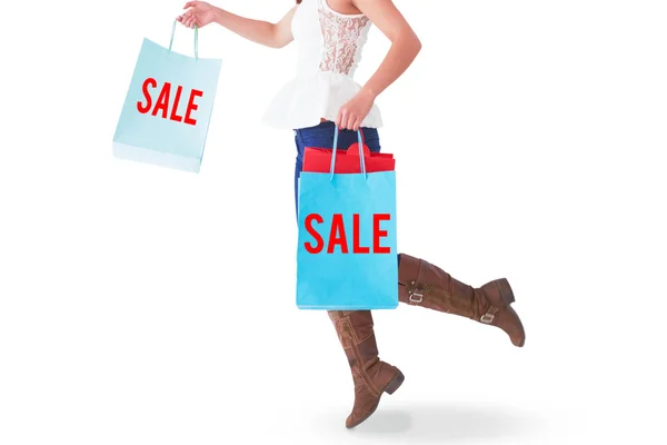 Happy brunette leaping with shopping bags — Stock Photo, Image