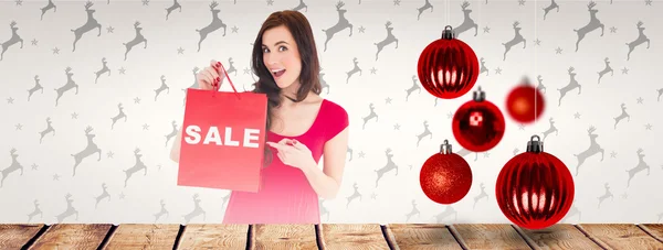 Stylish brunette in red dress showing sale bag — Stock Photo, Image