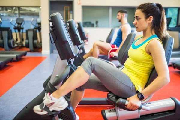 Hombre y mujer usando máquinas de ejercicio — Foto de Stock