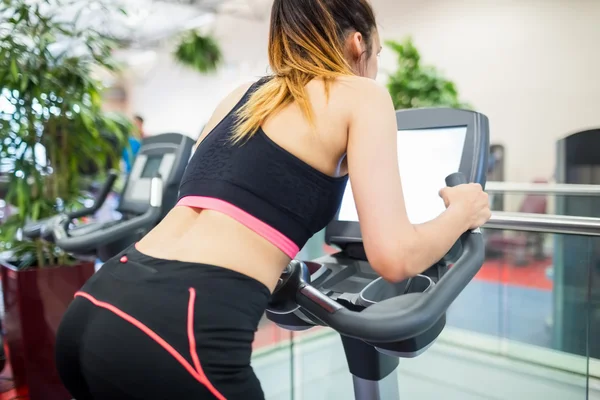 Mulher em uma bicicleta de exercício — Fotografia de Stock