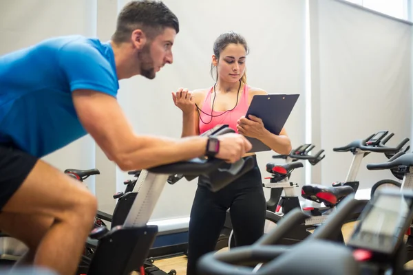 Tränare timing man på motionscykel — Stockfoto