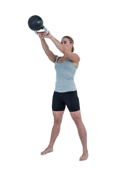 Serious muscular woman lifting kettlebell — Stock Photo, Image