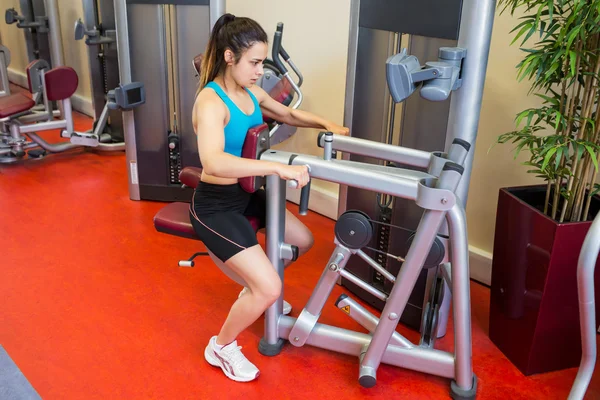 Focused woman using weights machine — Stock Photo, Image