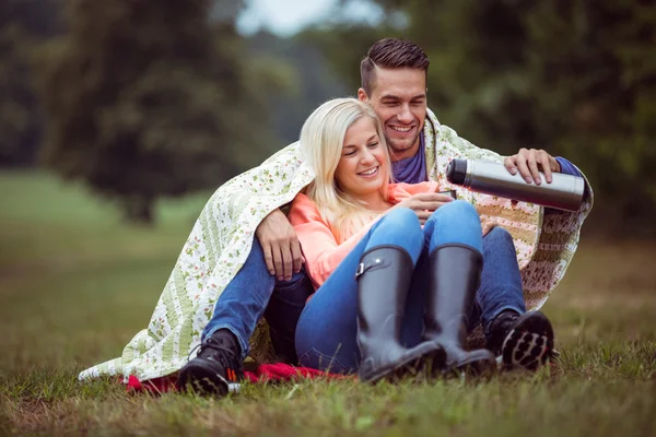 Feliz casal sentado sob cobertor — Fotografia de Stock