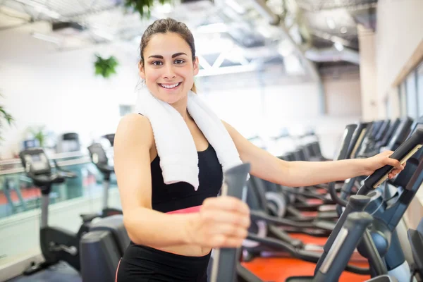 Femme souriante sur le cross trainer — Photo