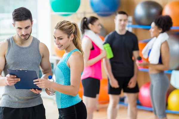 Client en trainer kijken naar Klembord — Stockfoto