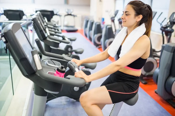 Mulher sorridente usando a bicicleta de exercício — Fotografia de Stock