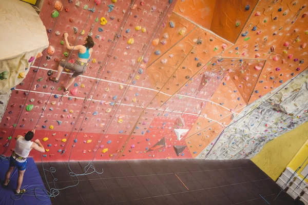 Woman climbing up rock wall — Stock Photo, Image