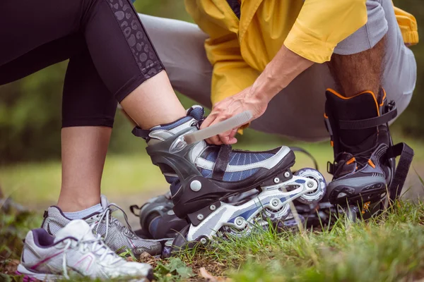 Gelukkige paar zetten roller blades — Stockfoto