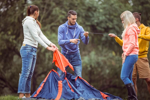 Счастливые друзья расставляют палатку. — стоковое фото