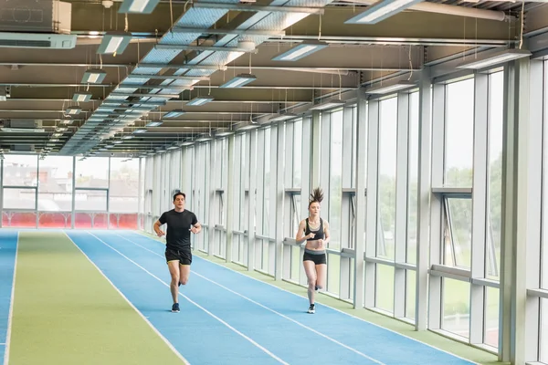 Casal correndo na pista interior — Fotografia de Stock