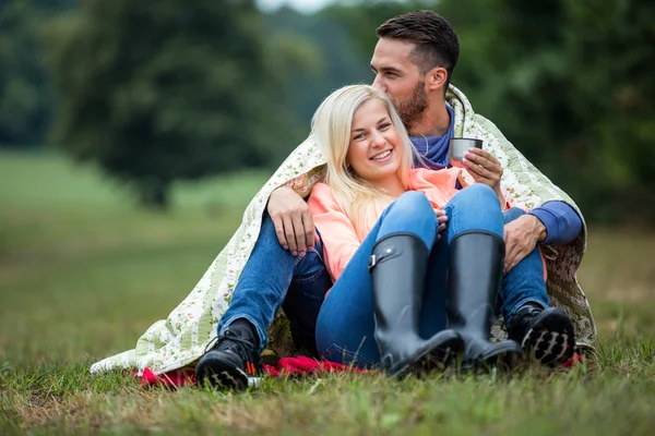 Feliz casal sentado sob cobertor — Fotografia de Stock
