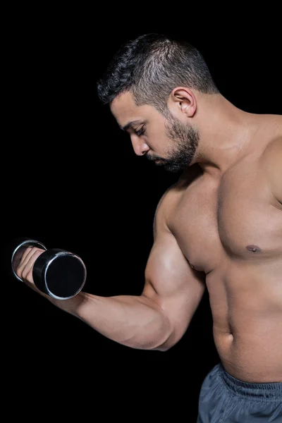 Homem musculoso levantando um halteres — Fotografia de Stock