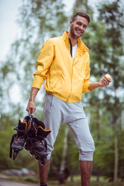 Hombre guapo sosteniendo patines en línea —  Fotos de Stock