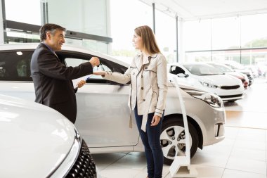 Salesman offering car key to a customers clipart