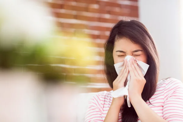 Asiática mujer soplando su nariz en sofá — Foto de Stock