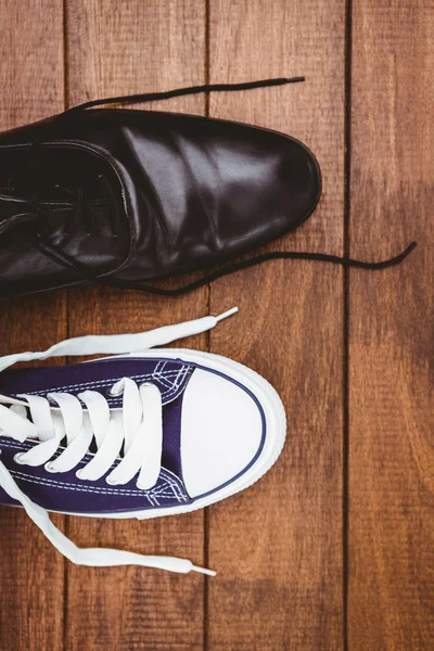 Twee verschillende schoenen op houten plank — Stockfoto