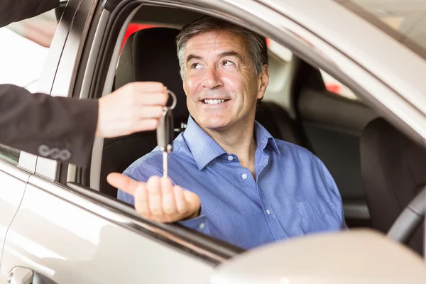 Salesman giving keys to a smiling businessman — Stock Photo, Image