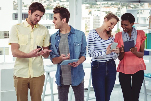 Sorrindo equipe criativa de pé em uma linha usando a tecnologia — Fotografia de Stock