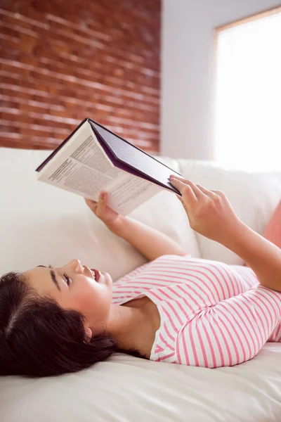 Sorrindo asiático mulher no sofá leitura — Fotografia de Stock