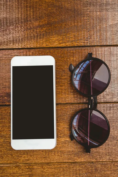 Gafas y un smartphone en escritorio de madera —  Fotos de Stock