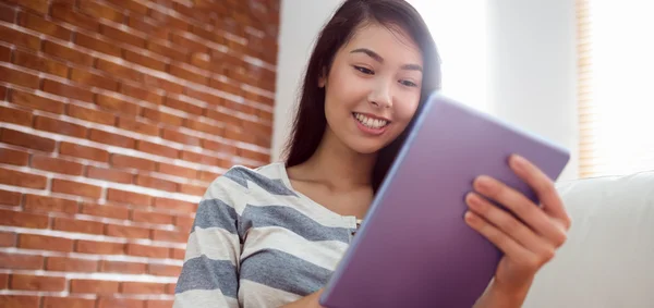 Lachende Aziatische vrouw met behulp van Tablet PC op Bank — Stockfoto