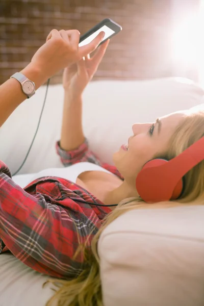 Ładna blondynka słuchanie muzyki na kanapie — Zdjęcie stockowe