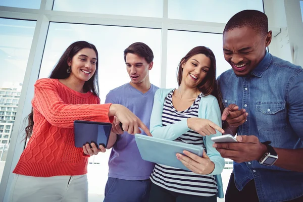 Creatieve team kijken naar telefoons en tabletten — Stockfoto