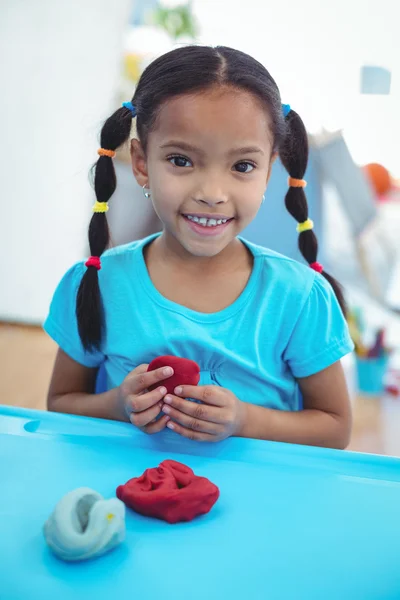 Smiling girl using modelling clay — Stock Photo, Image