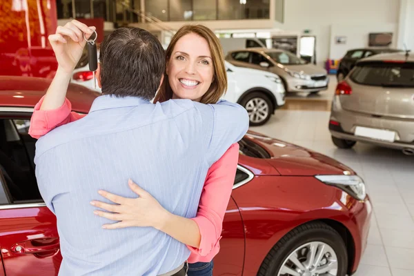 Woman holding key hugging husband — Stock Photo, Image