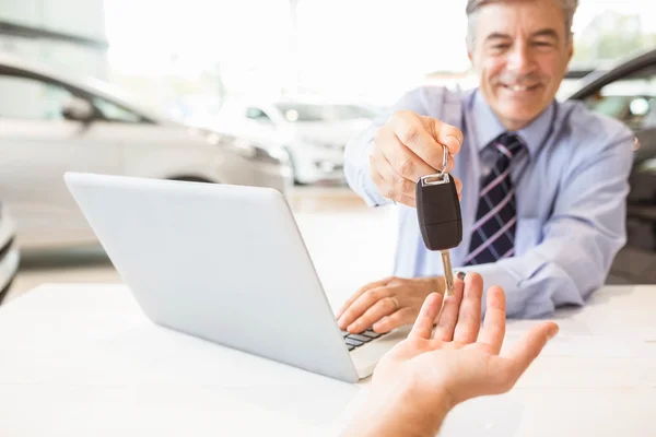 Vendedor segurando uma chave do carro do cliente — Fotografia de Stock