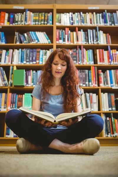 Mature student reading book in library — Stock Photo, Image