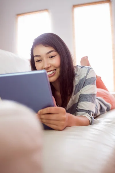 Sorrindo mulher asiática no sofá usando tablet — Fotografia de Stock